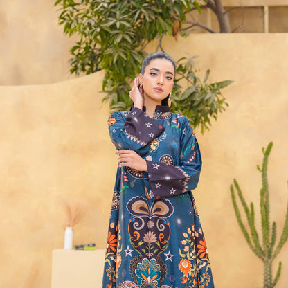 Woman in a colorful patterned outfit standing against a beige wall with plants.