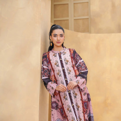 Woman in a floral dress standing against a beige wall with a plant in the background