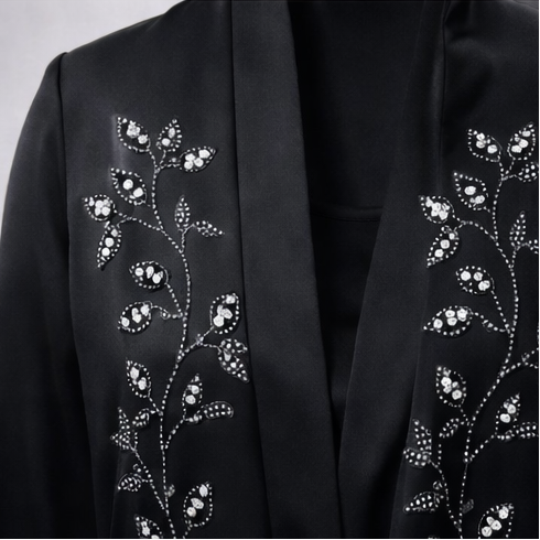 Black abaya with floral embroidery on a gray background