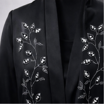 Black abaya with floral embroidery on a gray background